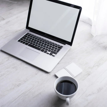 Minimalistischer Arbeitsplatz mit Laptop, Notizbuch und Kaffee – ideal für fokussiertes Arbeiten und digitale Klarheit im Business-Alltag.