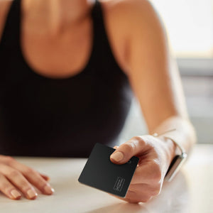 Frau hält den SPARTANHUB Card Finder, schlanker Geldbeutel-Tracker für unterwegs
